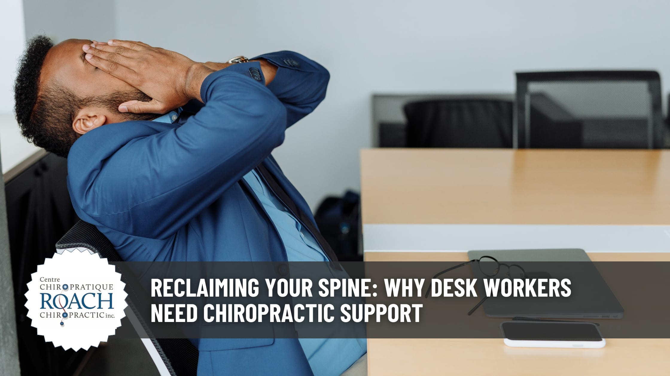 a man sitting at a desk, leaning back with hands on his face.